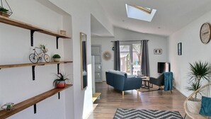 A modern living room with wooden shelves, a sofa, a chair, and a TV. - So Chic Kerfily, un Petit Coin de Paradis Breton Avec Espace SPA (Locmaria-Plouzané)