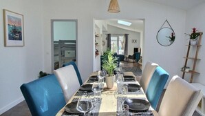 A dining area with a long table set for six, blue chairs, and a potted plant in the center. - So Chic Kerfily, un Petit Coin de Paradis Breton Avec Espace SPA (Locmaria-Plouzané)