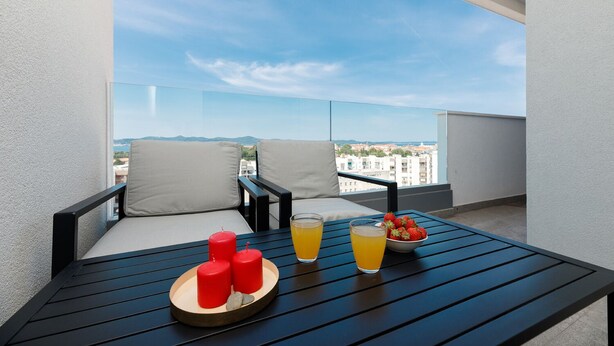 Ein Balkon mit zwei Stühlen, einem Tisch und Blick auf die Stadt.