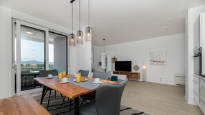 Ein moderner Essbereich mit Holztisch, grauen Stühlen und einer Glasabtrennung.