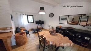 A cozy room with a wooden dining table, chairs, a television, and a large mirror. - Chalet à Proximité de L'océan Avec Piscine Insolite (Queyrac)