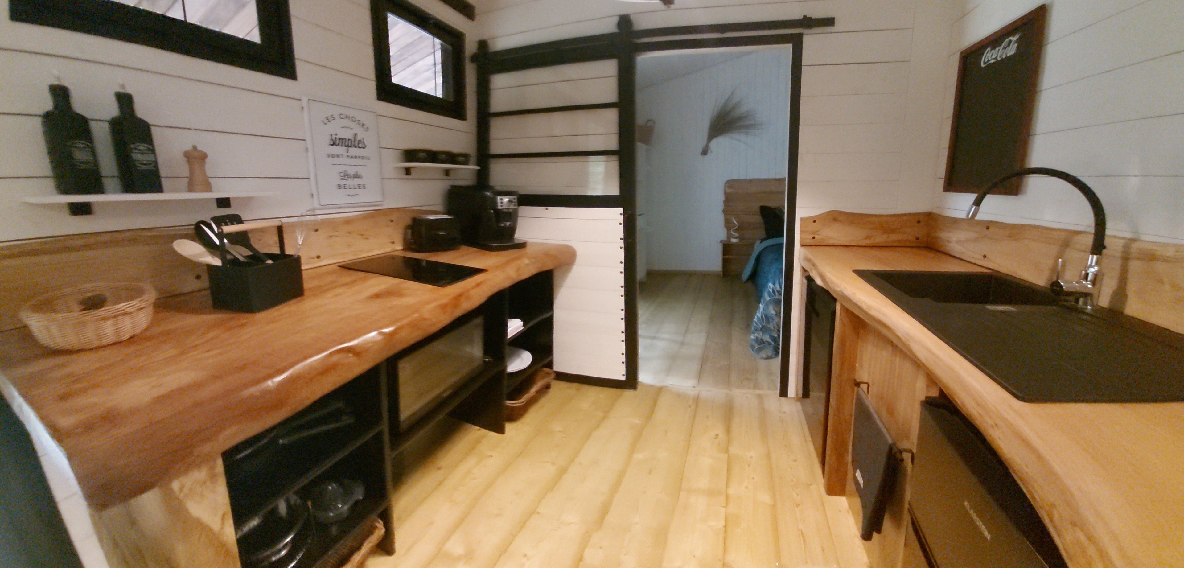 Une cuisine compacte dotée de plans de travail en bois, d’une machine à café et d’un évier.