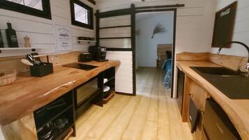 Une cuisine compacte dotée de plans de travail en bois, d’une machine à café et d’un évier.