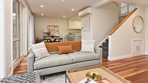 Una sala de estar moderna con un sofá gris, una mesa de centro y una escalera.