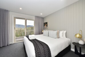 Una habitación de hotel con una cama, una mesita de noche, una lámpara, un cuadro y vistas al exterior.