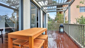 A wooden deck with a table and benches, a railing, and a view of the surrounding area.