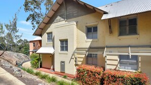 A two-story house with a sloped roof, multiple windows with shutters, and a front porch.