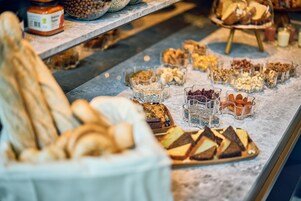 A bakery display with various breads, pastries, and jars of spreads.
