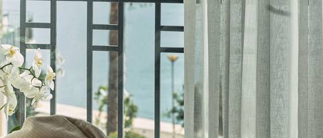A balcony with a view of the sea, a railing, and a plant.