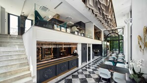 Een moderne hotellobby met een geruite vloer, een bar en een trap naar een hoger niveau.
