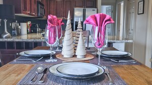 A dining table set with plates, cutlery, and napkins in a kitchen with wooden cabinets and a refrigerator. - Pet-Friendly 2-Bedroom Condo Near Hot Springs (Radium Hot Springs)