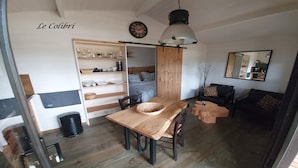 Um espaço de estar acolhedor com uma mesa de jantar de madeira, um sofá e uma estante.