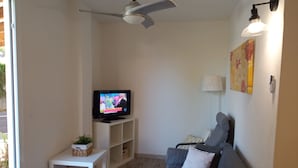A living room with a television, a ceiling fan, a sofa, a small table, and a lamp. - CAP DE MAR (Alcudia)