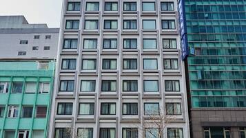 Een meerlaags hotel met een moderne gevel, met een symmetrisch raam patroon en een opvallend blauw bord aan de rechterkant.