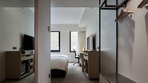 Une chambre d’hôtel avec un lit, un bureau, une télévision et un miroir.