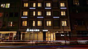 Un hôtel à plusieurs étages, avec des fenêtres illuminées et une enseigne.