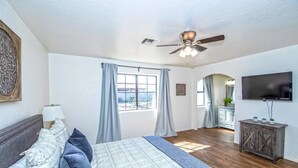 A bedroom with a bed, a ceiling fan, a TV, and a view of the outside. - LUXURY Living 2 (Yuma)