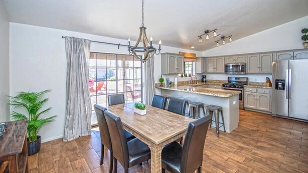 A spacious kitchen with a large island, modern appliances, and a dining area with a wooden table and chairs. - LUXURY Living 2 (Yuma)