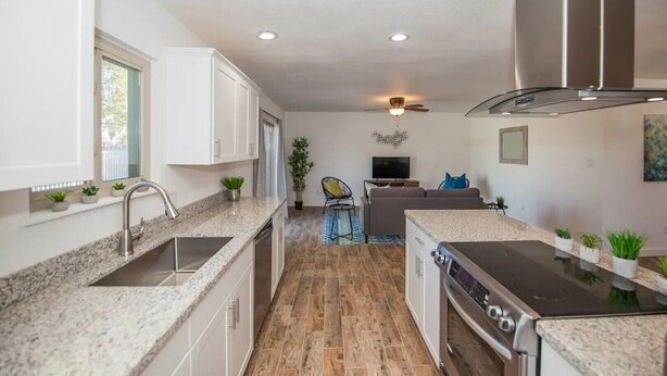 A modern kitchen with granite countertops, white cabinets, and a built-in oven. - LUXURY Living 3 (Yuma)