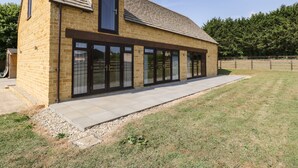 A single-story brick building with a sloped roof, large sliding glass doors, and a small attached garage. - Petals Patch (Cheltenham)