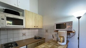 A compact kitchen with a microwave, coffee maker, and a stove.
