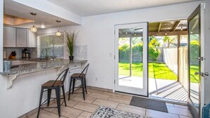 A kitchen with a large island, bar stools, and a sliding glass door leading to a backyard. - LUXURY Living 4 (Yuma)