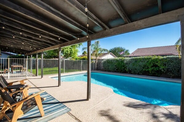 Un espace extérieur abrité avec une piscine, des chaises longues et une pergola.