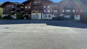 Un hotel de varios pisos con balcones de madera y un estacionamiento al frente.