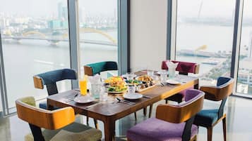 A dining table with chairs, plates, cutlery, and glasses, set against a city view.