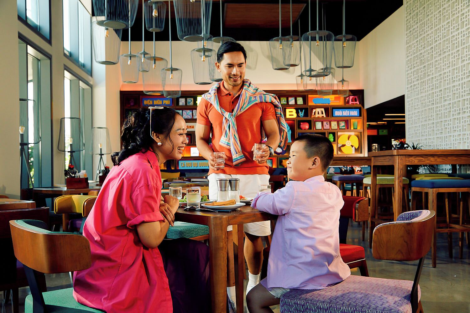 A restaurant with a modern interior, featuring hanging light fixtures and a variety of seating options.