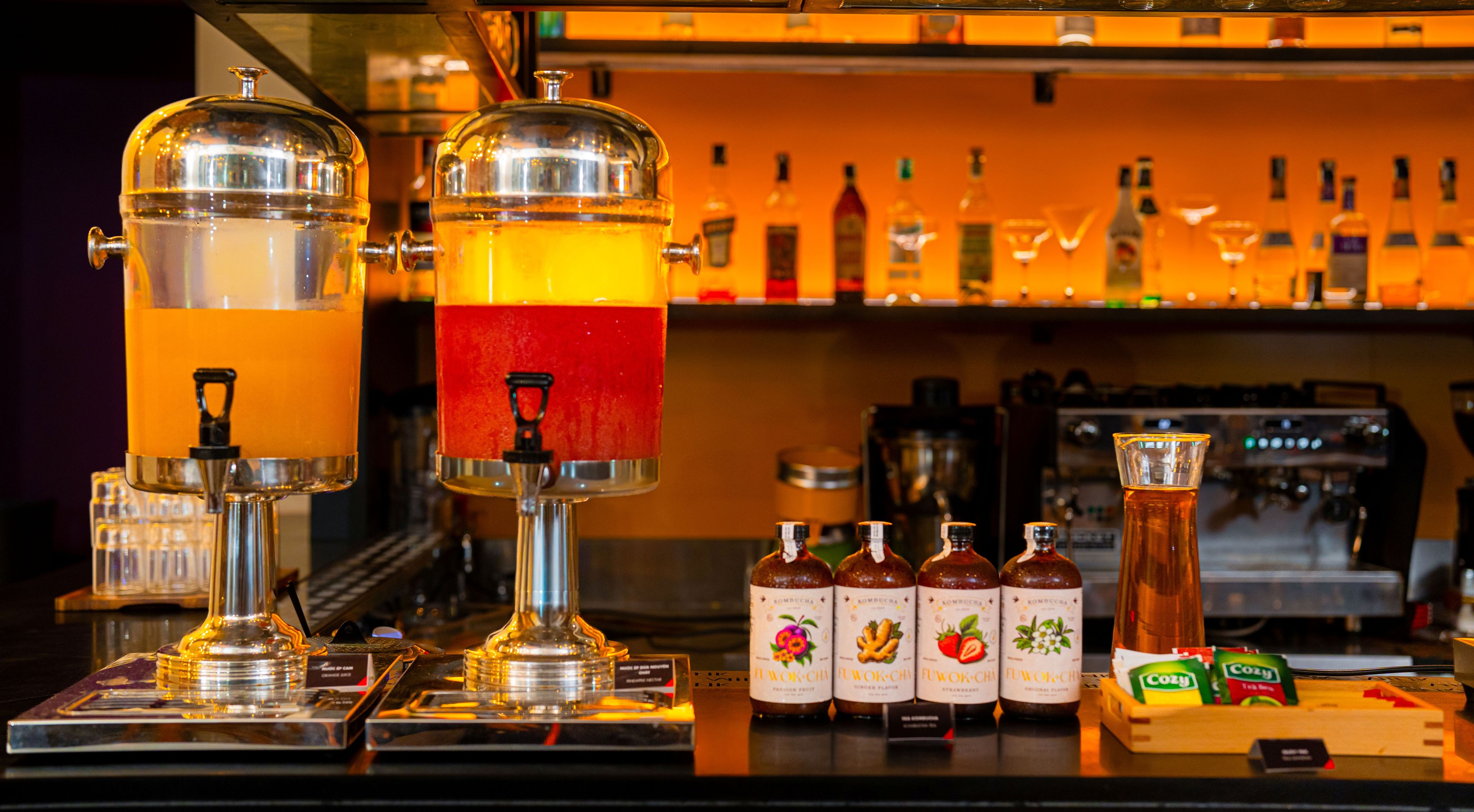 A bar area with two large dispensers, a selection of bottled beverages, and a coffee machine.