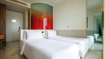 A hotel room with two beds, a large mirror, and a door leading to another room.