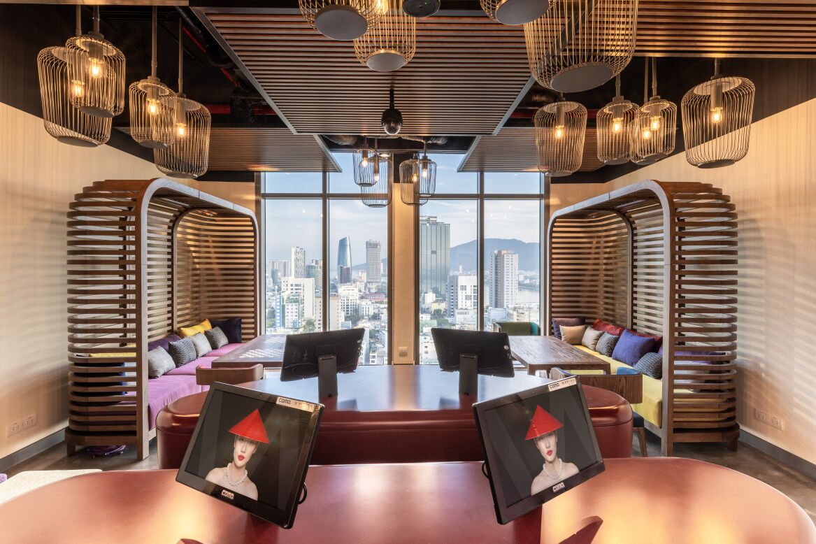 Uma sala de reunião moderna com vista para a cidade, assentos em níveis diferentes e iluminação pendente.