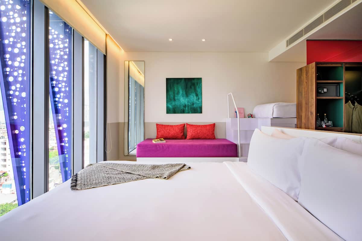 Een moderne hotelkamer met een groot bed, een kleine zithoek, een bureau en een kledingkast.