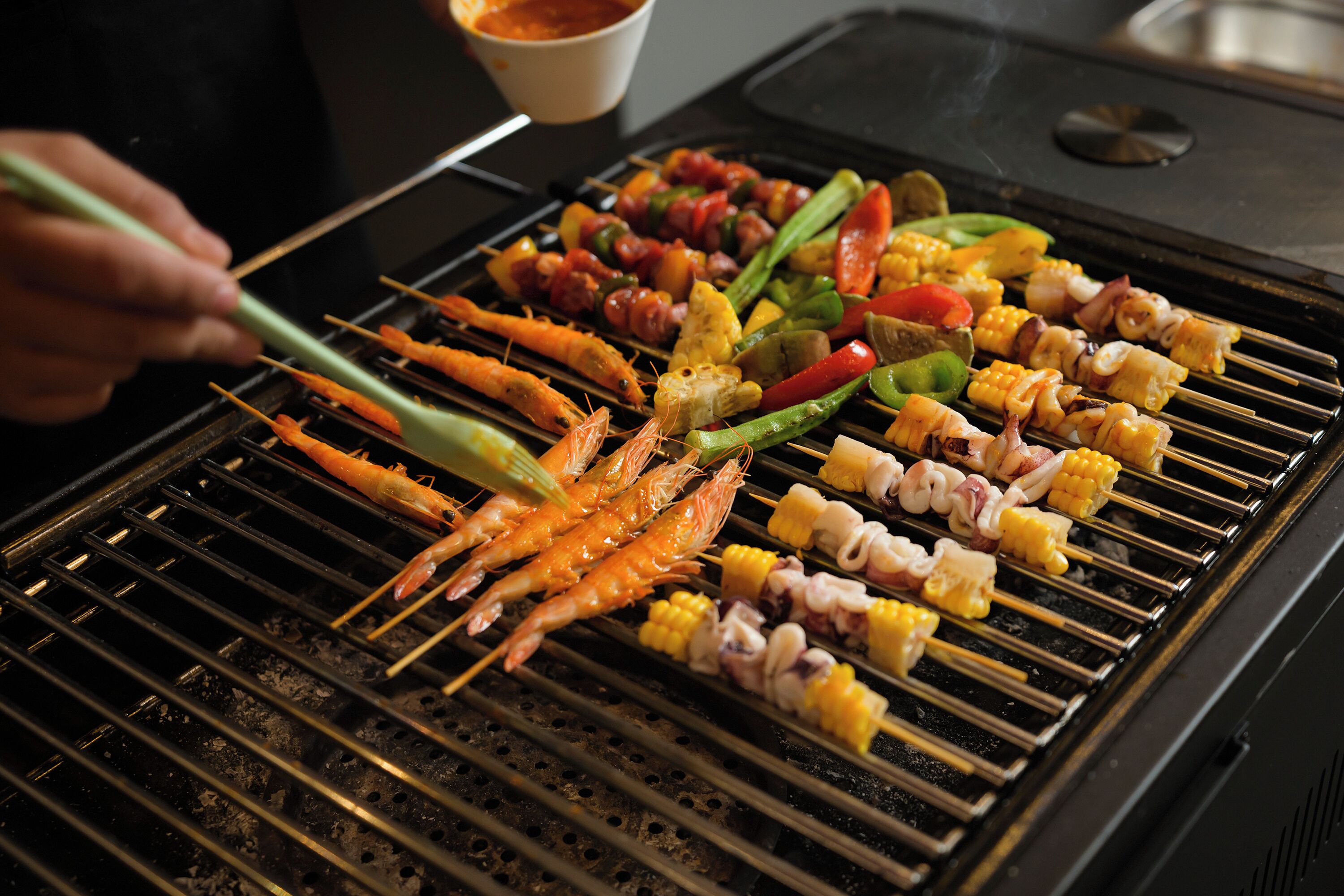 A grill with various skewers of seafood and vegetables.