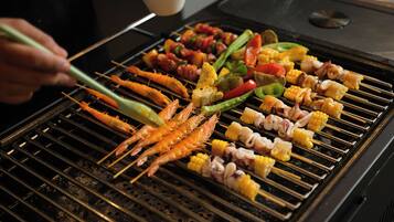 A grill with various skewers of seafood and vegetables.