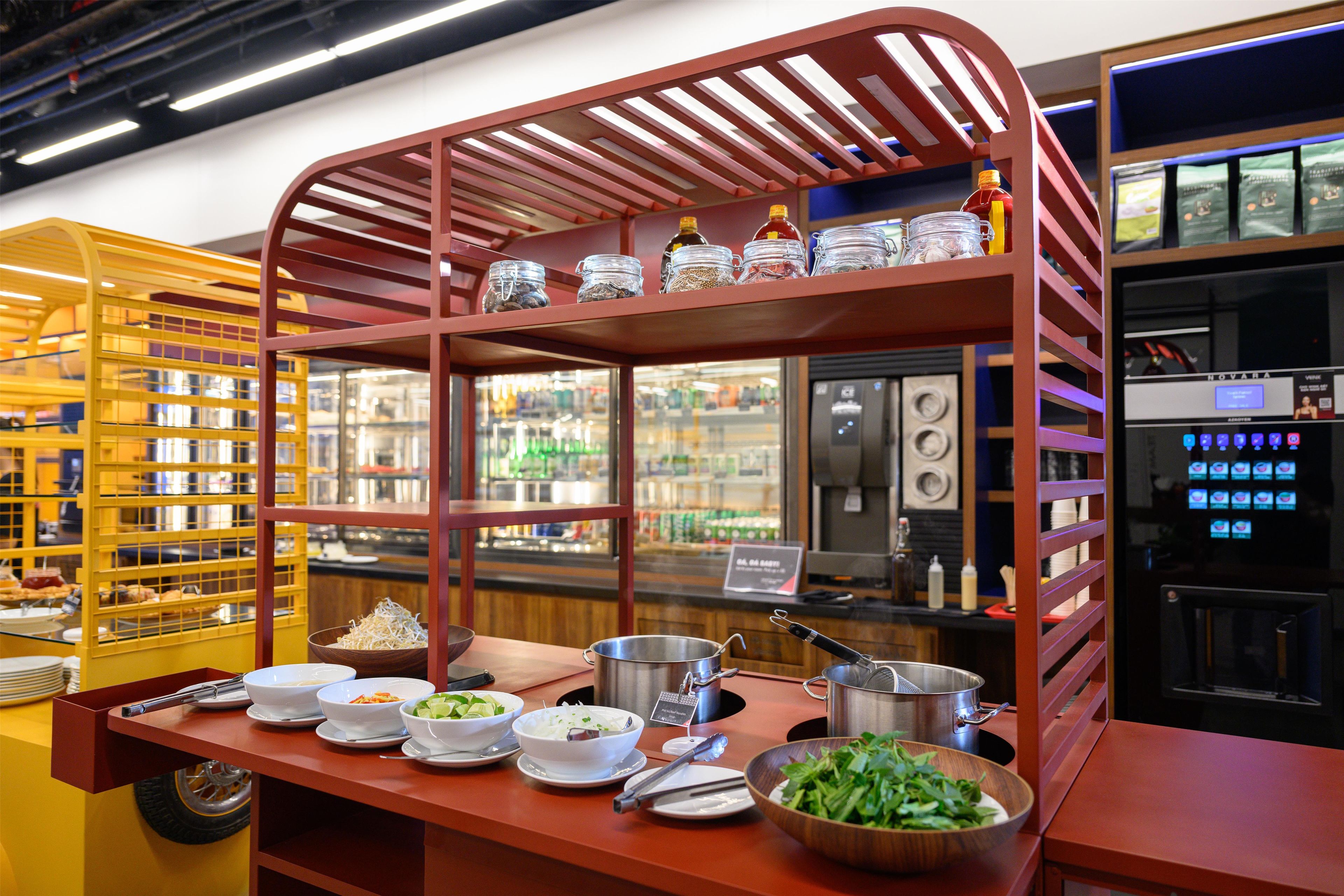 Un'impostazione buffet con diversi cibi, una macchina per caffè e un frigorifero.