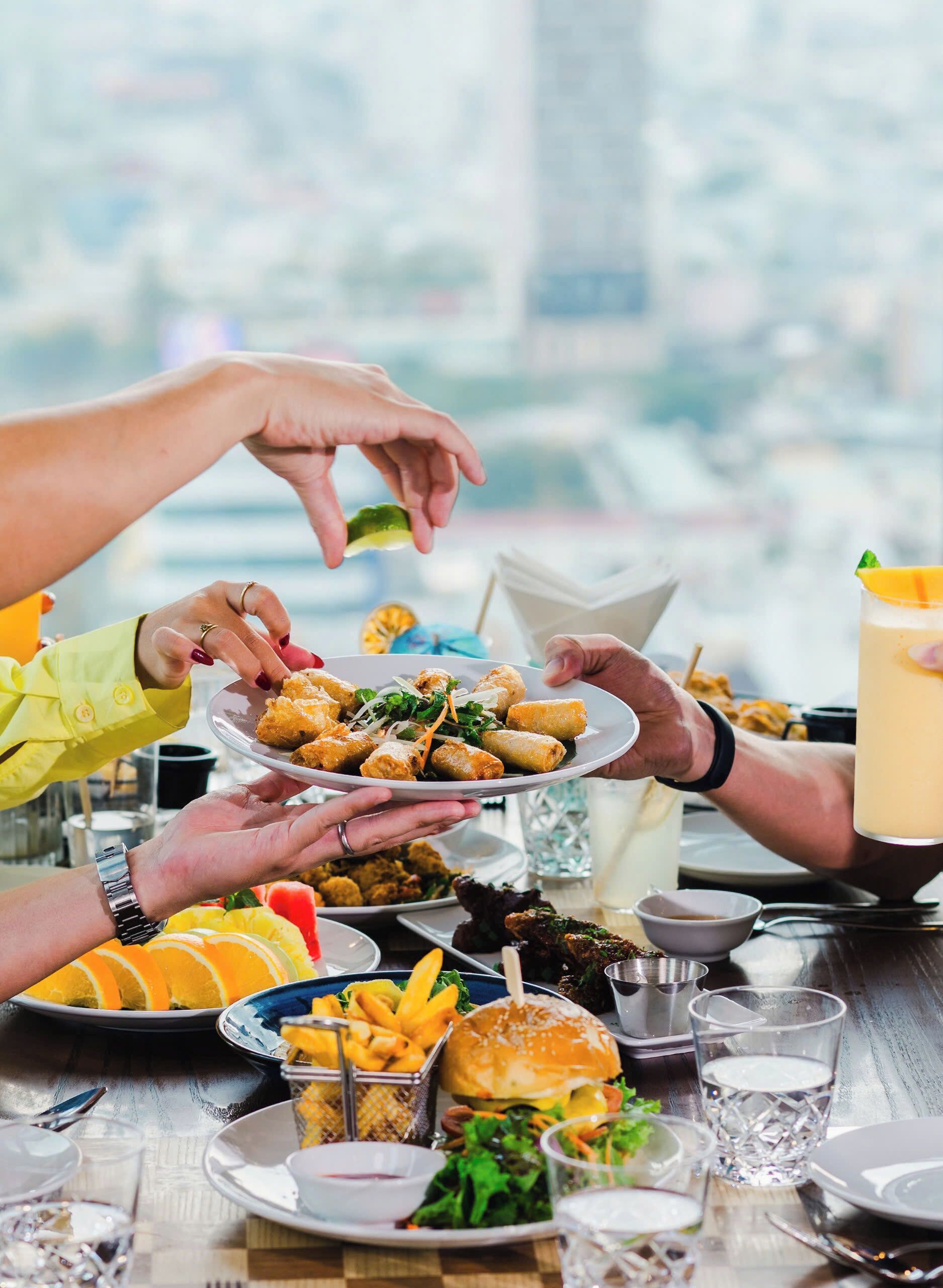 A group of people sharing a meal with various dishes and drinks on a table.