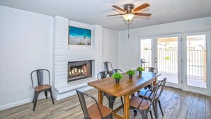 A dining area with a wooden table and chairs, a fireplace, and a ceiling fan. - LUXURY Living 5 (Yuma)