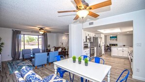 A modern living room with a dining table, blue chairs, and a ceiling fan. - LUXURY Living 5 (Yuma)