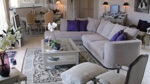 A living room with a sectional sofa, a glass coffee table, and a dining area with a chandelier. - Sainte Maxime (Sainte-Maxime)