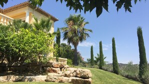 A well-maintained garden with a stone wall, a palm tree, and a building with a tiled roof. - Sainte Maxime (Sainte-Maxime)