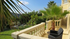 A balcony with a stone balustrade, a palm tree, and outdoor furniture. - Sainte Maxime (Sainte-Maxime)