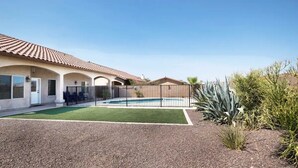 A residential property with a swimming pool, a fenced patio area, and a well-maintained lawn. - Luxury Living 6 (Yuma)