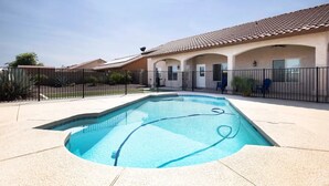 A rectangular swimming pool with a tiled deck, surrounded by a black metal fence. - Luxury Living 6 (Yuma)