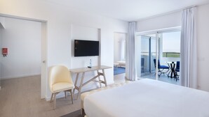 A hotel room with a bed, a desk with a chair, a flat-screen TV, and a balcony with a table and chairs. - Royal Obidos Villas & Apartments (Obidos)