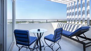 A balcony with a glass table and chairs, a lounge chair, and a view of the cityscape. - Royal Obidos Villas & Apartments (Obidos)