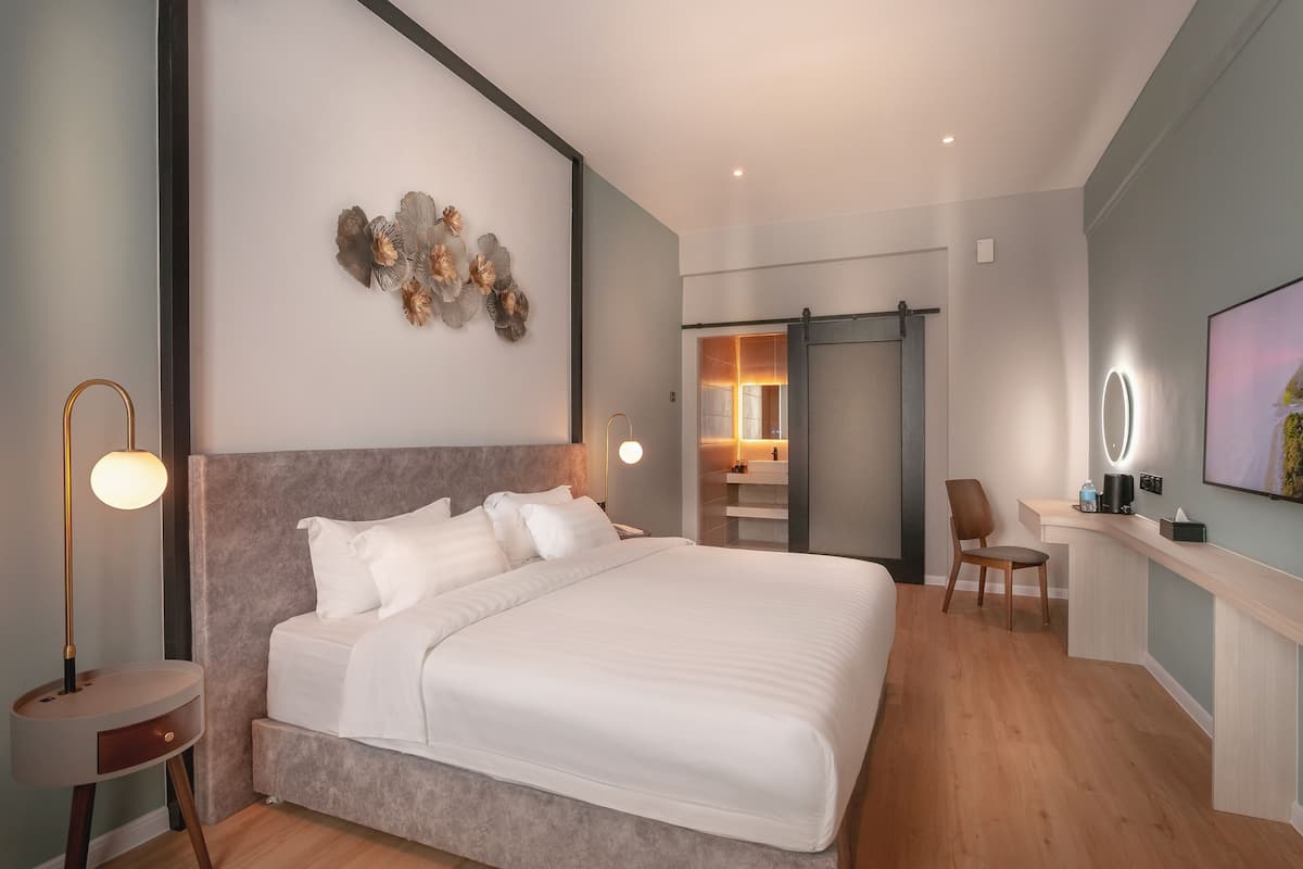Een moderne slaapkamer met een groot bed, nachtkastjes, een bureau en een stoel.