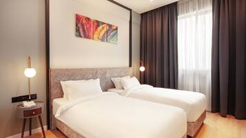 A hotel room with two beds, a modern headboard, a painting on the wall, and a large window with curtains.