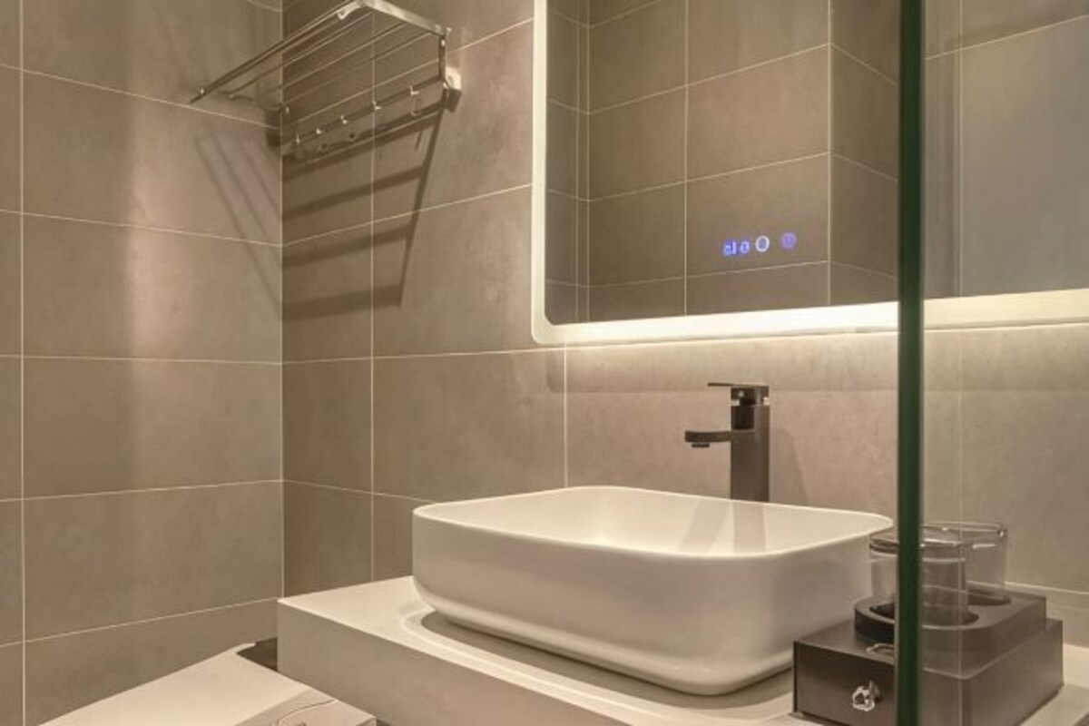 A modern bathroom with a large rectangular sink, a mirror, and a towel rack.